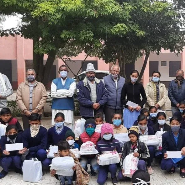 Schoolchildren and volunteers in masks holding bundles, 2020