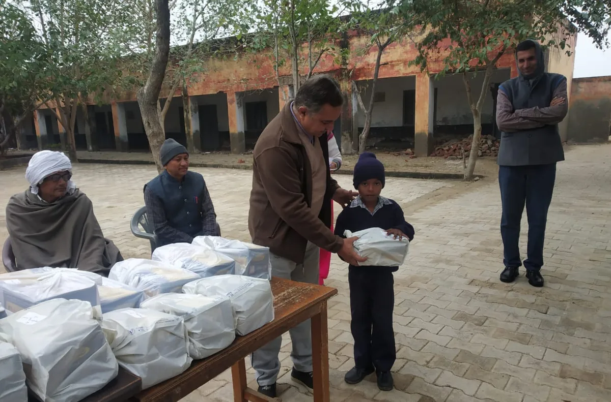 A volunteer handing a bundle of winter clothes to a boy at a table