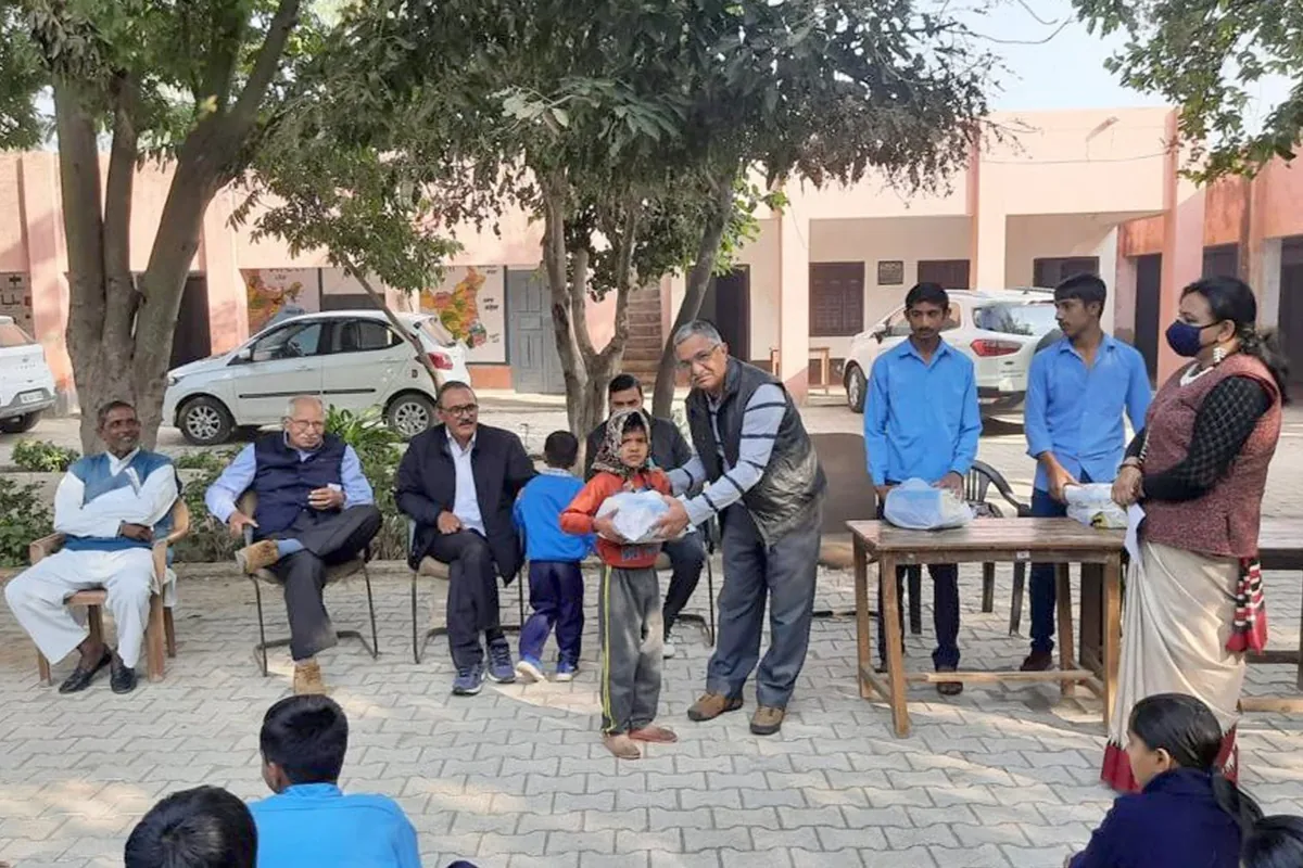 Volunteers giving a bundle of winter clothes to a child